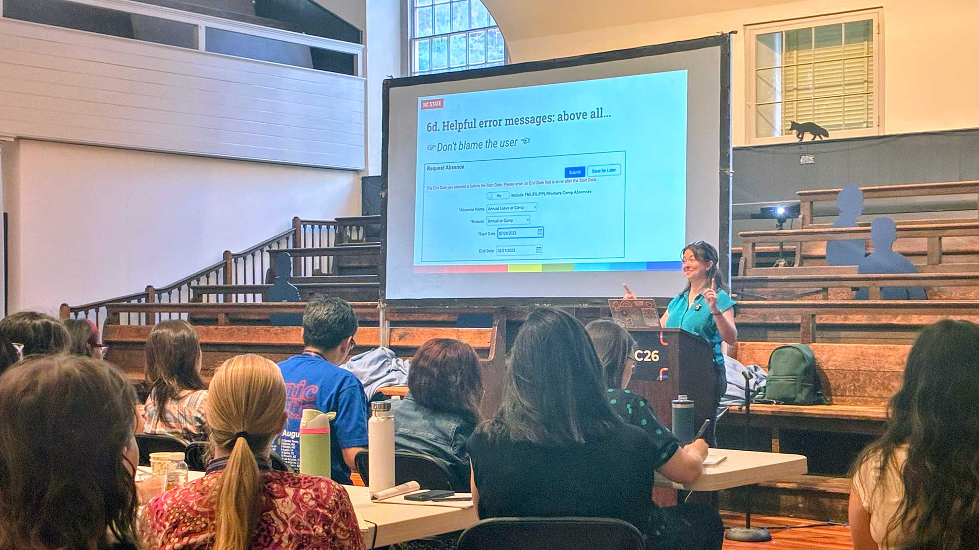 Robin presenting in front of a screen that says, Helpful error messages, above all, do not blame the user